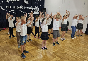 przedszkolaki podczas tańca stoją w rzędach i machają rękami w górze
