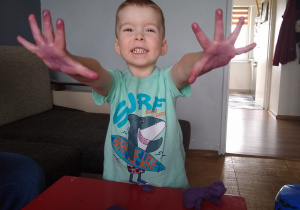 chłopiec pokazuje zafarbowane fioletowe dłonie