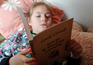 dziewczynka leży i czyta książkę