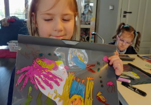 dziewczynka pokazuje pracę o morzu wykonaną mazakami do malowania na folii