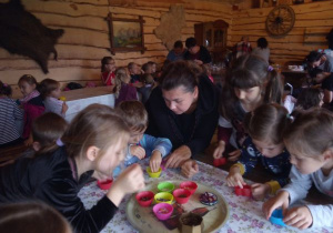 dzieci z nauczycielką przy stole dotykają różne ziarna umieszczone na tacy w kolorowych pojemnikach