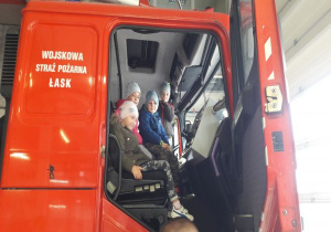 dzieci siedzą w kabinie wozu strażackiego