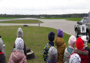 dzieci oglądają lądowanie samolotu na pasie startowym