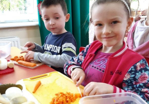 dzieci kroją marchewki na deskach