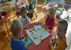 dzieci kroją jabłka przy stoliku