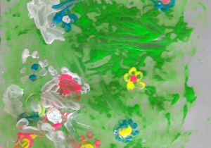 prac plastyczna: zielona łąka wystemplowana chusteczką a na niej wystemplowane patyczkiem do uszu kolorowe kwiatki