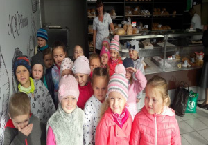 grupa dzieci stoi w sklepie z pieczywem przed ladą