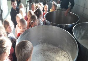 dzieci zaglądają do dużych naczyń z wsypaną mąką