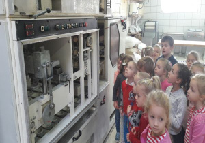 dzieci zaglądają maszynę do formowania pączków