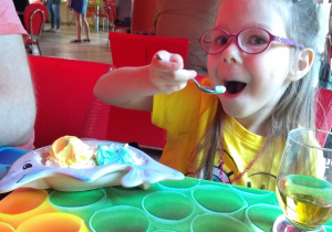 dziewczynka siedzi i je kolorowe lody