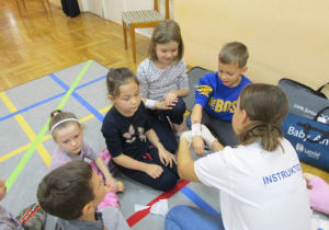 instruktorka bandażuje rękę dziewczynki
