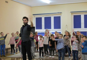 dzieci tańczą z prowadzącym wyciągają jedna rękę do przodu