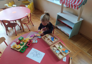 dziewczynka układa drewniane lalki z elementów