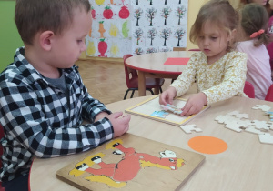 chłopiec i dziewczynka układają drewniane puzzle