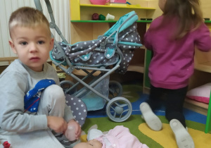 chłopiec z dziewczynką bawia się kąciku dom wózkiem i lalką
