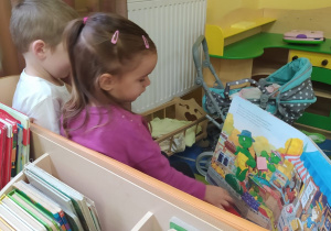 dziewczynka z chłopcem oglądają książkę siedząc na ławce w kąciku dom
