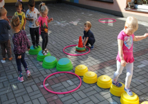 dzieci na tarasie przedszkolnym idą po zielonych i żółtych stopniach