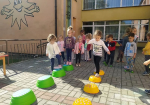 na tarsie maluszki na tarasie biorą udział w zawodach sportowych i przechodzą po ustawionych w rzędzie podestach - zielonych i żółtych