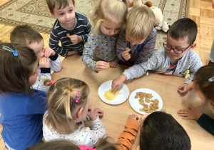 dzieci jedzą ciasteczka i maczają je w miodzie wlanym na talerzyku