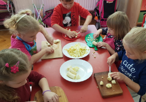 dzieci kroja jabłka i banany na sałatkę owocową