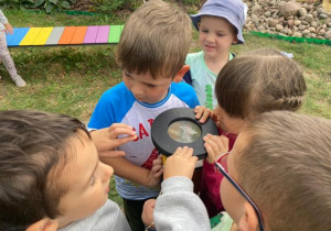 dzieci poznają lupę w ogrodzie na terenie ogródka "Słoneczna Akademia"