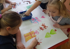 dziewczynki przy stoliku rysują renifera i paczki