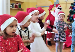 dzieci pokazują ruchy ilustrujące piosenkę, którą śpiewają Mikołajowi