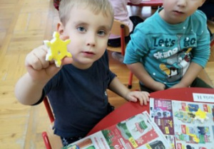 chłopiec pokazuje ozdobę na choinkę - żółtą gwiazdę