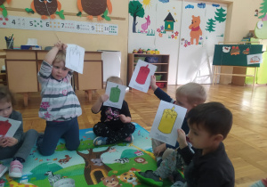 dzieci pokazują wylosowane kartki ze świeczkami w rożnych kolorach