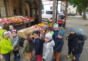 dzieci stoją przed straganem z owocami