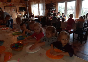 dzieci gniotą ciasto na kolorowych talerzach