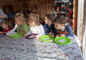 dzieci siedzą przy stole i mają mąkę na talerzach