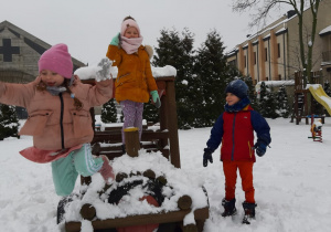 dzieci stoją na lokomotywie na placu zabaw podczas zabaw na śniegu