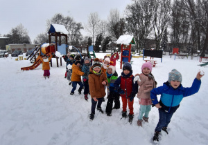 dzieci stoja w rzędzie i rzucają kulkami śniegowymi