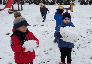 chłopcy trzymają duże kule śniegowe