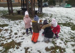 dzieci bawią się przy wielkiej kuli śnieżnej