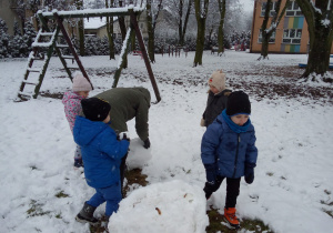 dzieci z panią toczą kule śniegowe