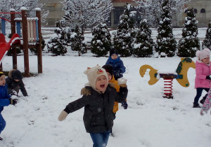 dzieci biegną po śniegu i rzucają kulkami sniegowymi