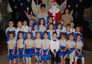 zdjęcie grupowe dzieci z gr7 w biało- niebieskich strojach Mikołajem i nauczycielkami