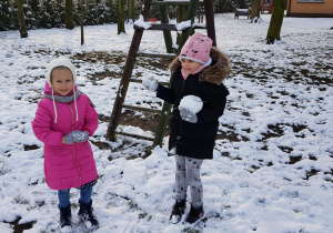 dwie dziewczynki trzymają w rękach kulki śniegowe