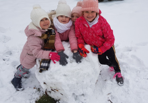 4 dziewczynki opierają się o wielką kulę śniegową