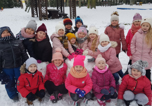 w ogrodzie dzieci z grupy VI pozują do zdjęcia przy wielkiej kuli śniegowej