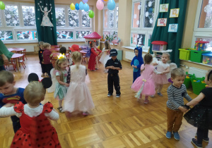 dzieci w strojach balowych tańczą parami w sali