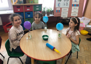 trzy dziewczynki pokazują butelki z solą i z balonami na butelkach