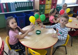dzieci pokazują butelki z kolorowymi balonami na butelkach