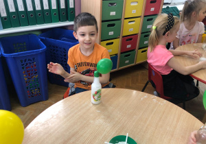 chlopiec obserwuje jak zielony balon umieszczony na butelce rośnie