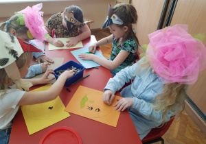 dziewczynki w opaskach na głowie: kwiatów i ptaszków rysują planety na kolorowych kartkach