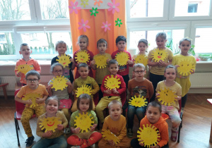 dzieci z grupy V pokazują wykonane przez siebie słońca z żółtego papieru