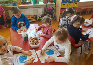 dzieci przy stolikach kolorują rysunek Warszawskiej Syrenki
