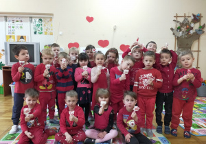dzieci w czerwonych ubraniach z grupy IX z lizakami w kształcie serduszek